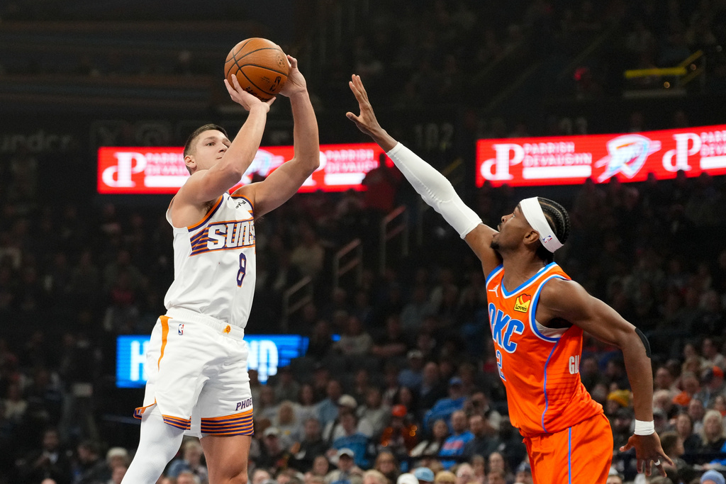 Phoenix Suns guard Grayson Allen, left, shoots over Oklahoma City Thunder guard Shai Gilgeous-Alexander, rifght, during the first half of an NBA Cup basketball game, Wednesday, Dec. 10, 2025, in Oklahoma City. (AP Photo/Kyle Phillips)