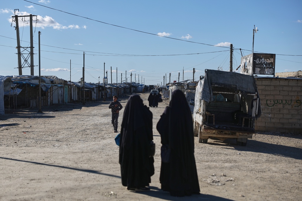 Residents walk along the al-Hol camp, one of the detention facilities holding thousands of Islamic State group members and their families, now under the control of the Syrian government following the withdrawal of the Syrian Democratic Forces (SDF), in al-Hassakeh province, northeastern Syria, Wednesday, Feb. 4, 2026. (AP Photo/Ghaith Alsayed)