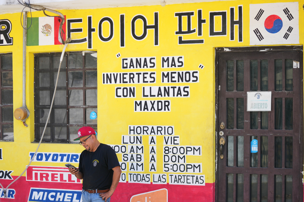 Small business owner Mario Alberto Cantú stands outside his tire repair shop, with words in both Spanish and Korean displayed across the storefront in Pesqueria, Mexico, Tuesday, March 31, 2026. (AP Photo/Fernando Llano)