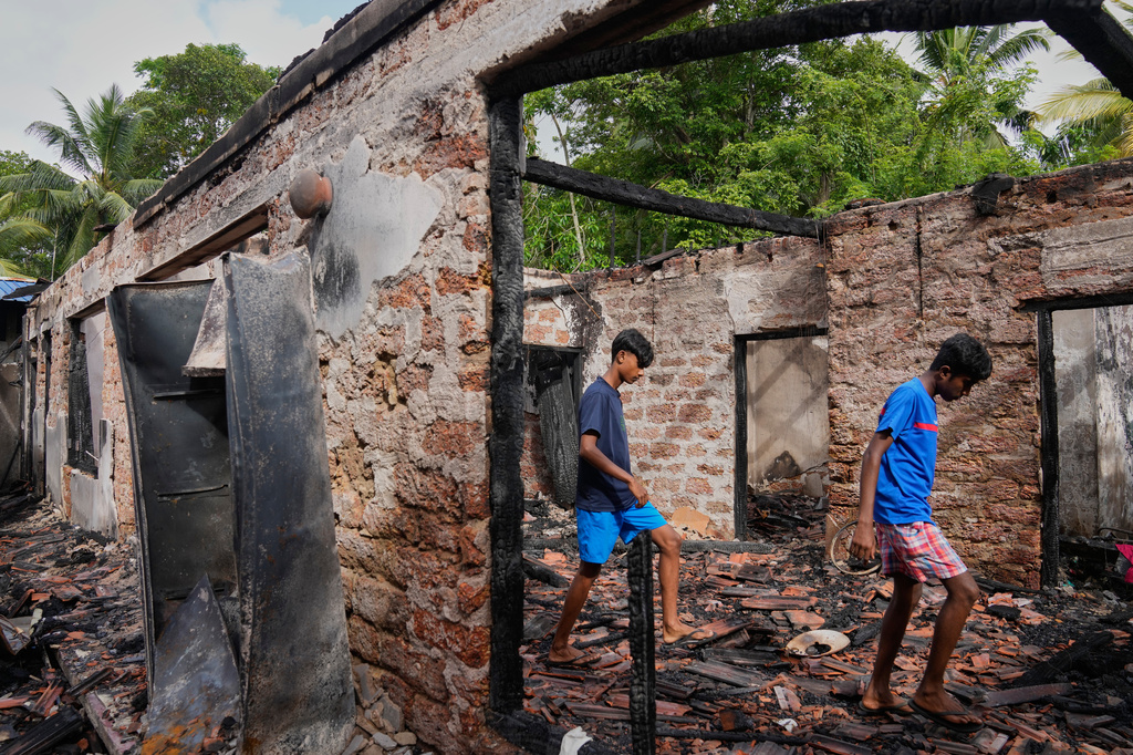 Villagers walk through the debris of a nursing home which caught fire in Anguruwatota, Sri Lanka, Friday, June 5, 2026. (AP Photo/Eranga Jayawardena)