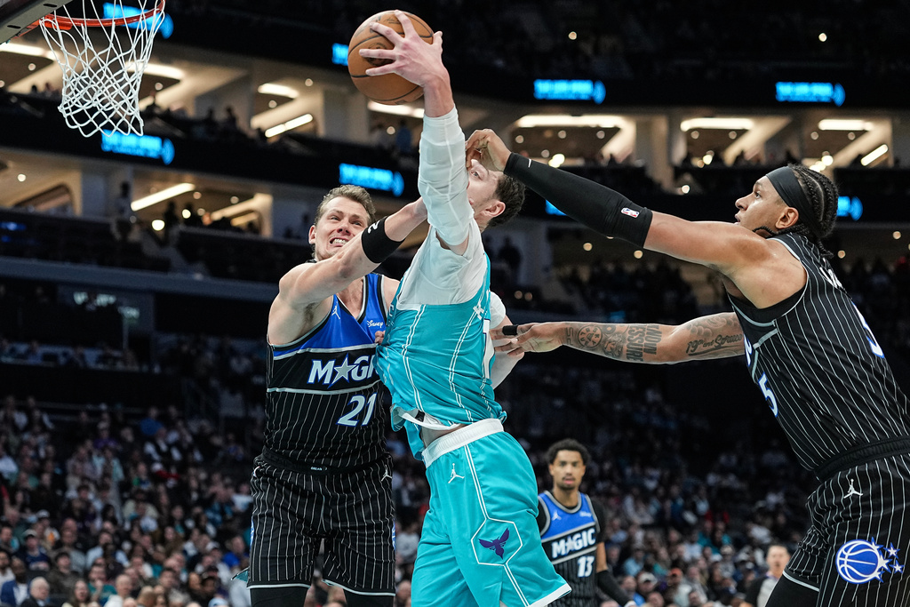 Charlotte Hornets center Ryan Kalkbrenner (11) battles for a loose ball with Orlando Magic forward Moritz Wagner (21) and forward Paolo Banchero (5) during the first half of an NBA basketball game, Thursday, March 19, 2026, in Charlotte, N.C. (AP Photo/Matt Kelley)