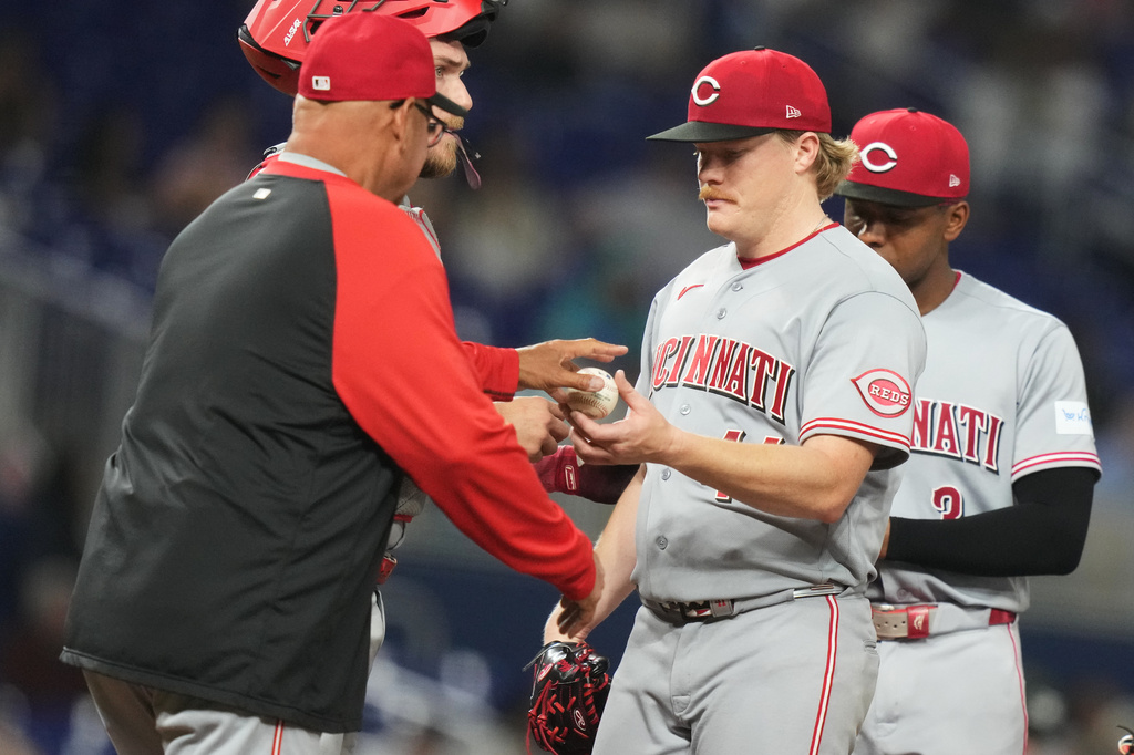 Cincinnati Reds pitcher Andrew Abbott, center, hands the ball to manager Terry Francona, left, as he is relieved in the sixth inning of a baseball game against the Miami Marlins, Tuesday, April 7, 2026, in Miami. (AP Photo/Lynne Sladky)