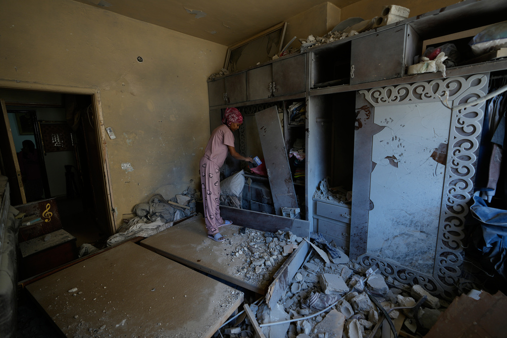 A domestic worker cleans a damaged bedroom in the southern port city of Tyre, Lebanon, Thursday, April 30, 2026 as the homeowner returns to the house. (AP Photo/Hussein Malla)