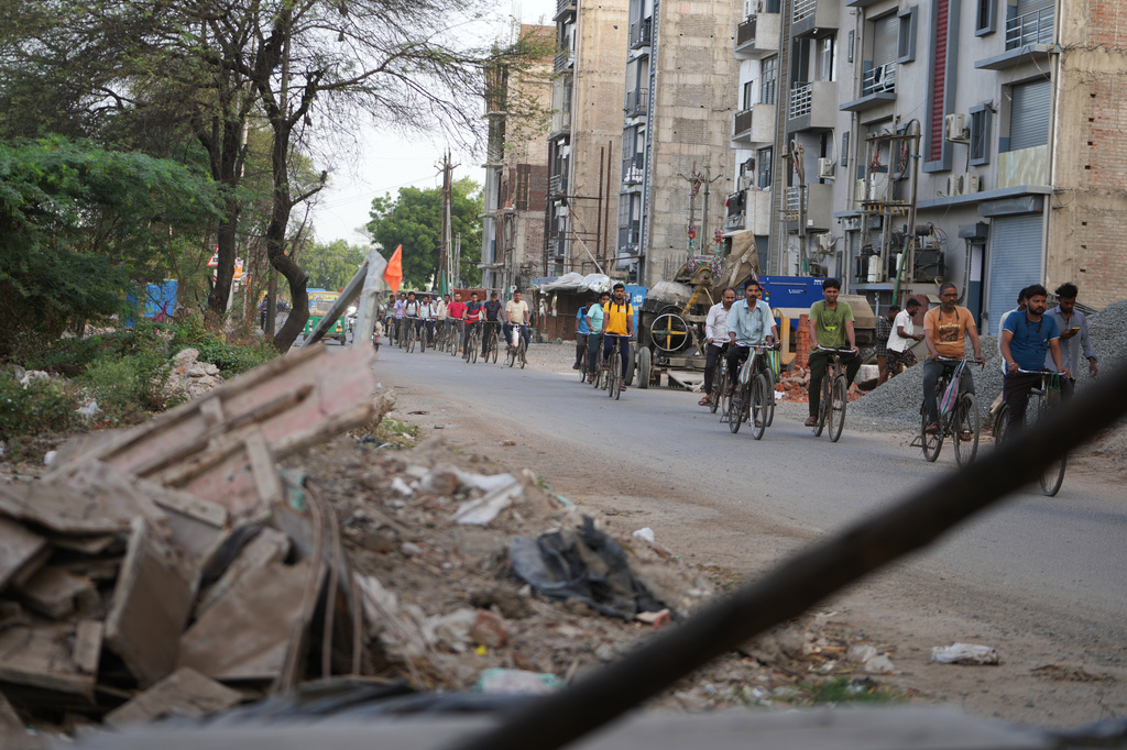 Power loom factory workers cycle to work in Surat, India, Thursday, May 28, 2026. (AP Photo/Ajit Solanki)