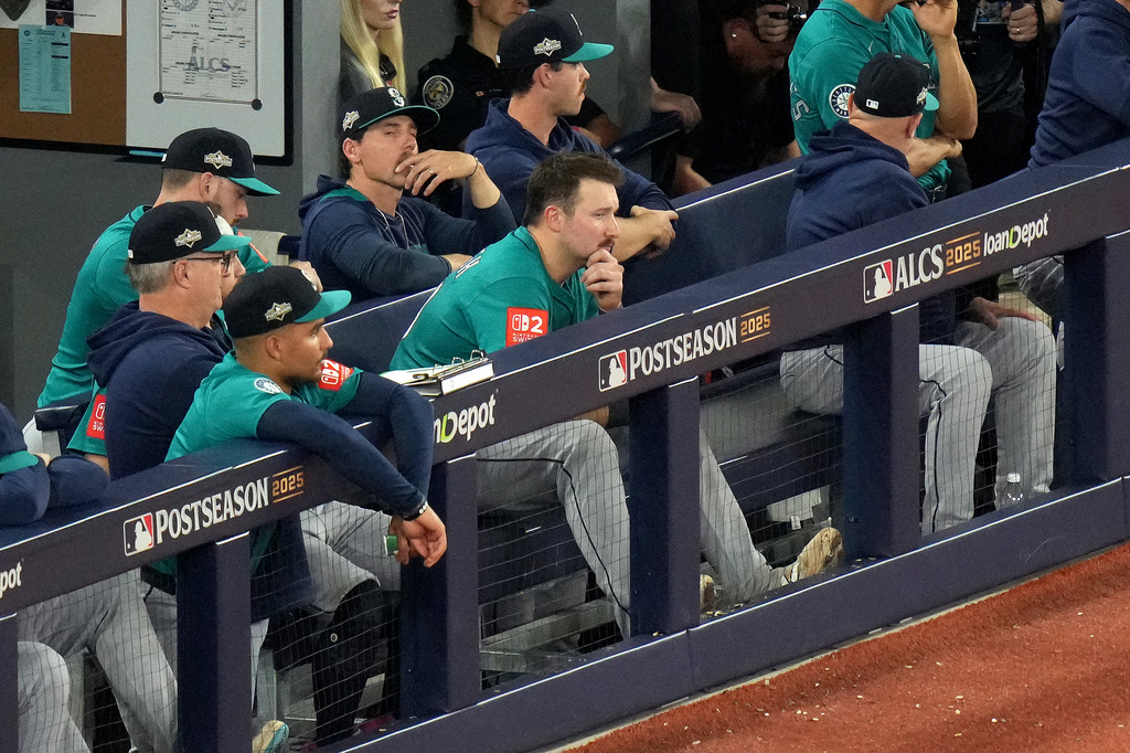 Seattle Mariners catcher Cal Raleigh, center without hat, sits in the dugout during their loss to the Toronto Blue Jays during the ninth inning of Game 6 of baseball's American League Championship Series in Toronto, Sunday, Oct. 19, 2025. (Chris Young/The Canadian Press via AP)