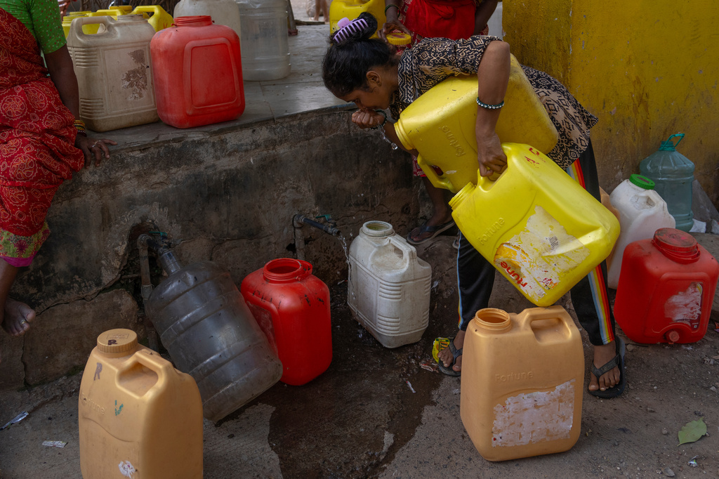 Aishah Khan, a resident of a slum settlement, checks the quality of water from a public tap in Mumbai, India, Saturday, June 20, 2026. (AP Photo/Rafiq Maqbool)