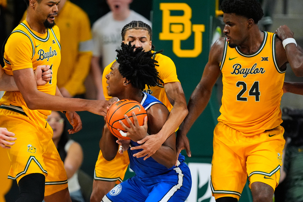 BYU guard Robert Wright III, center, works to take a shot as Baylor's Caden Powell, left, Cameron Carr, rear, and Tounde Yessoufou (24) defend in the second half of an NCAA college basketball game Tuesday, Feb. 10, 2026, in Waco, Texas. (AP Photo/Tony Gutierrez)