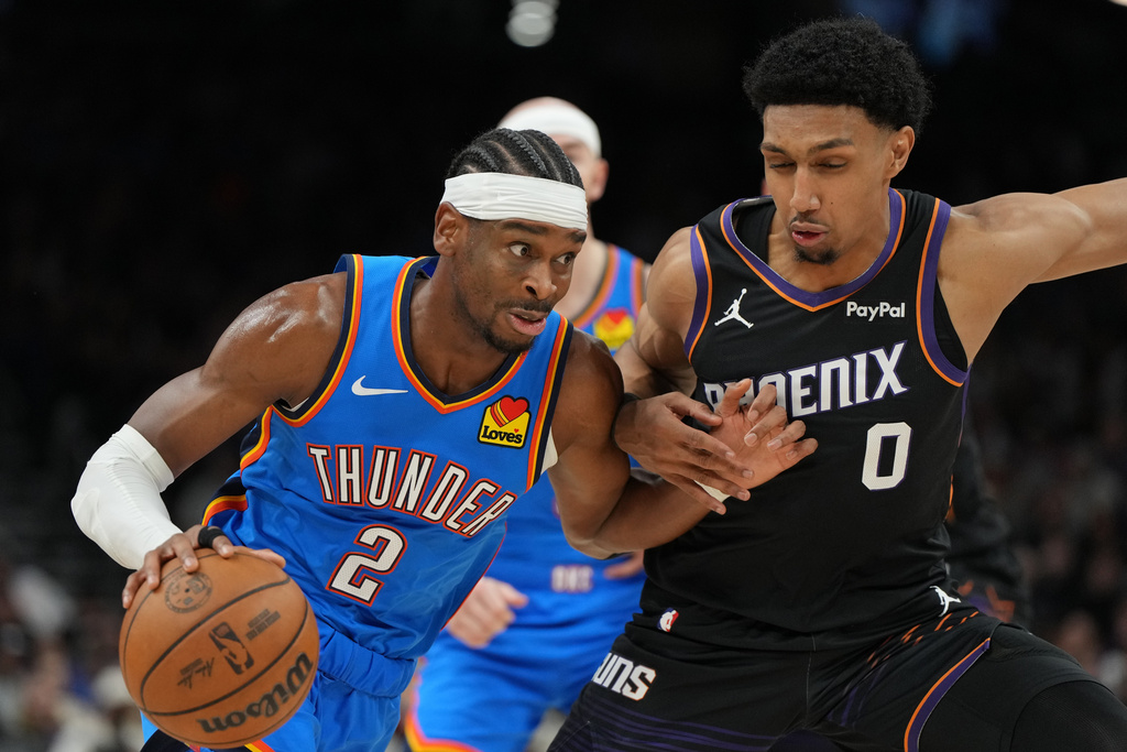 Oklahoma City Thunder guard Shai Gilgeous-Alexander (2) drives on Phoenix Suns forward Ryan Dunn during the second half of an NBA basketball game, Sunday, Jan. 4, 2026, in Phoenix. (AP Photo/Rick Scuteri)