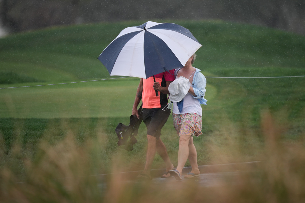 Fans walk in the rain along the fifth hole during the third round of the Arnold Palmer Invitational at Bay Hill golf tournament Saturday, March 7, 2026, in Orlando, Fla. (AP Photo/Matt Slocum)