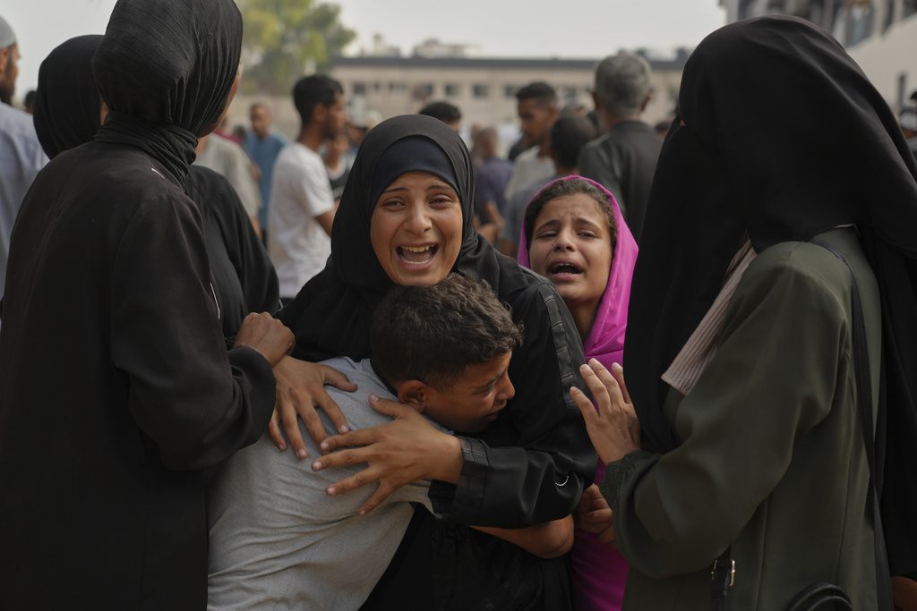 The mother of Mohammed Al-Sukni, center, who was killed while trying to reach aid trucks, is comforted by relatives outside Shifa Hospital, before his funeral in Gaza City, Thursday, Aug. 21, 2025. (AP Photo/Jehad Alshrafi)