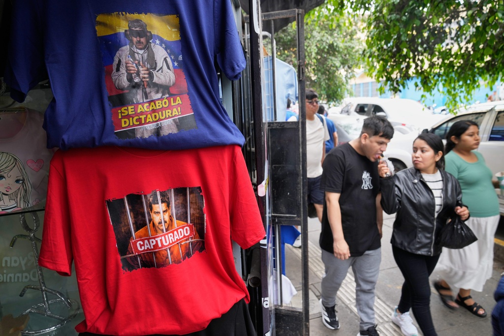 Pedestrians pass T-shirts featuring images of Venezuelan President Nicolas Maduro at at a printing shop in Lima, Peru, Monday, Jan. 5, 2026, two days after U.S. forces captured and removed him from Venezuela. (AP Photo/Martin Mejia)