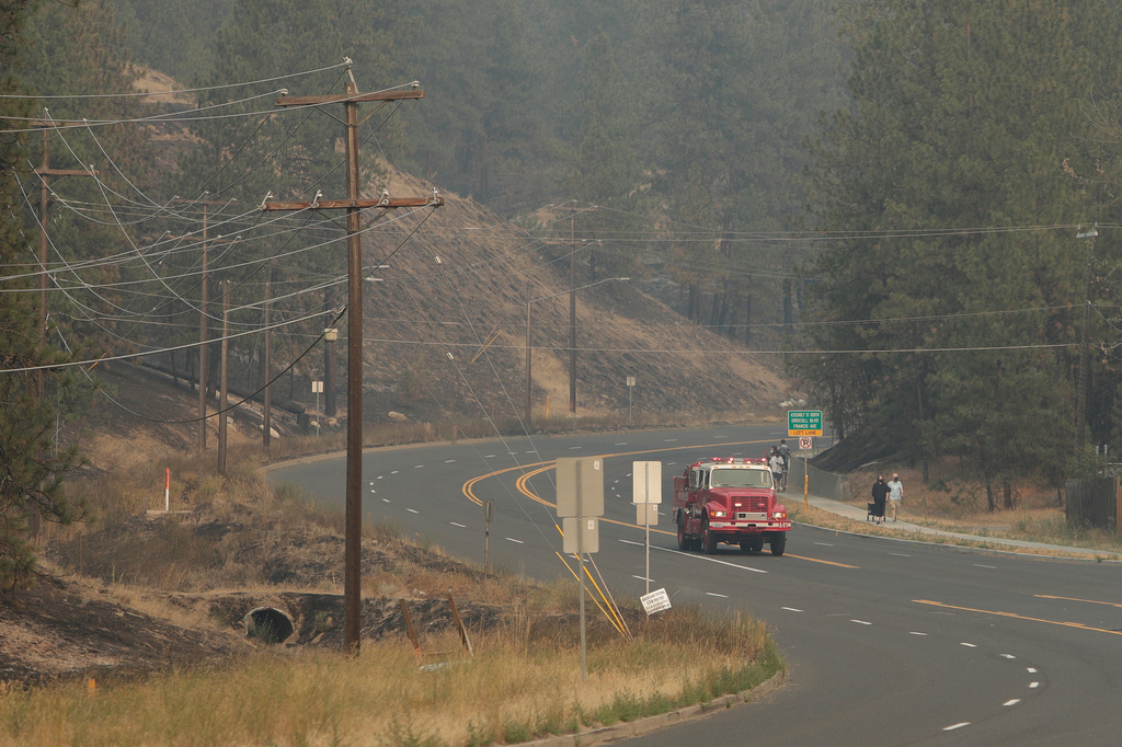 A fire truck travels past a previously burned wildfire area on W. Nine Mile Rd., Sunday, Aug. 2, 2026, in Spokane, Wash. (AP Photo/Young Kwak)