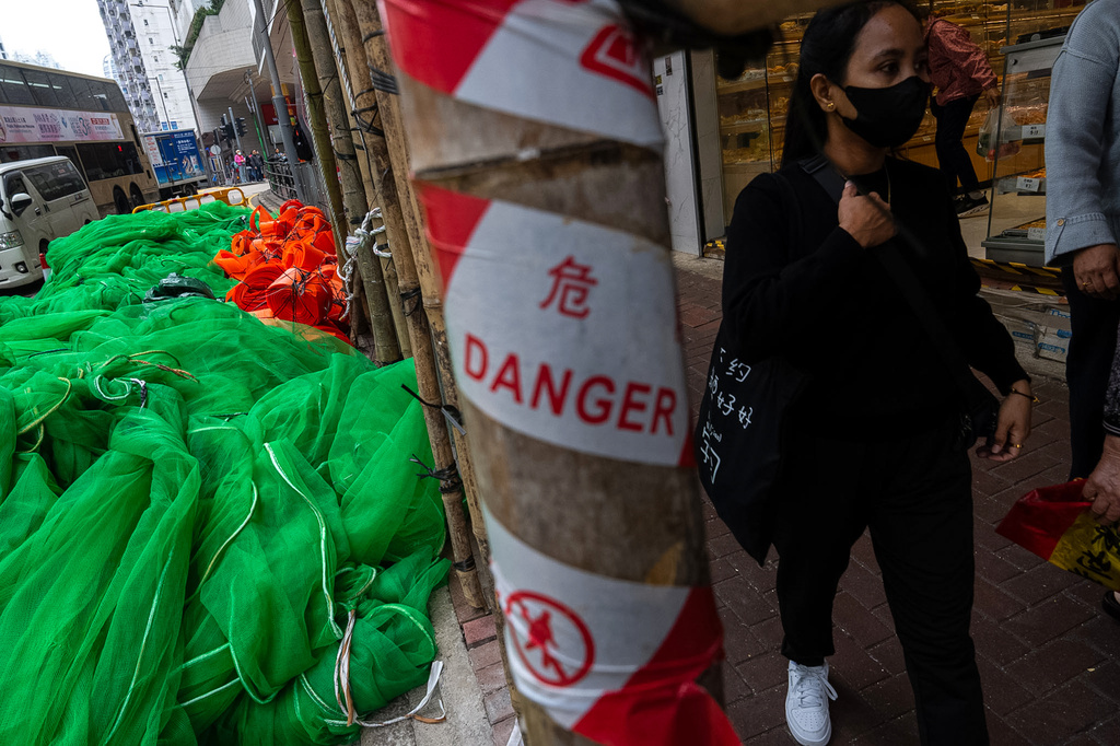 Pedestrians walk past the removed scaffolding nets and construction materials in Quarry Bay district after the deadly fire at Wang Fuk Court, in the Tai Po district of Hong Kong's New Territories, Thursday, Dec 4, 2025. (AP Photo/Chan Long Hei)