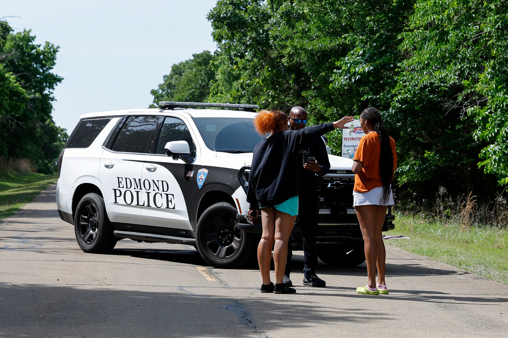 Two women talk to an Edmond police officer blocking the entrance to Scissortail Campground at Arcadia Lake, Monday, May 4, 2026, in Edmond, Okla., after a shooting on Sunday evening. (AP Photo/Alonzo Adams)