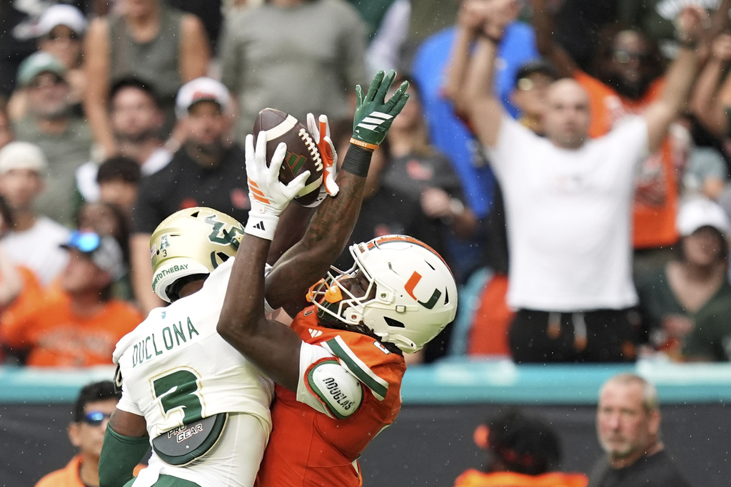 Miami wide receiver Joshua Moore, right, catches a pass to score a touchdown, defended by South Florida cornerback Jonas Duclona, during the first half of an NCAA college football game, Saturday, Sept. 13, 2025, in Miami Gardens, Fla. (AP Photo/Rebecca Blackwell)