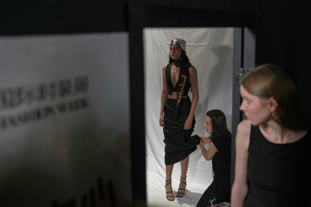 An assistant helps a model dress up in a creation by Maggie Ma in the backstage during the SS2026 China Fashion Week in Beijing, Sunday, Sept. 7, 2025. (AP Photo/Andy Wong)