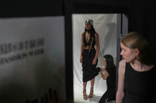 An assistant helps a model dress up in a creation by Maggie Ma in the backstage during the SS2026 China Fashion Week in Beijing, Sunday, Sept. 7, 2025. (AP Photo/Andy Wong) An assistant helps a model dress up in a creation by Maggie Ma in the backstage during the SS2026 China Fashion Week in Beijing, Sunday, Sept. 7, 2025. (AP Photo/Andy Wong)
