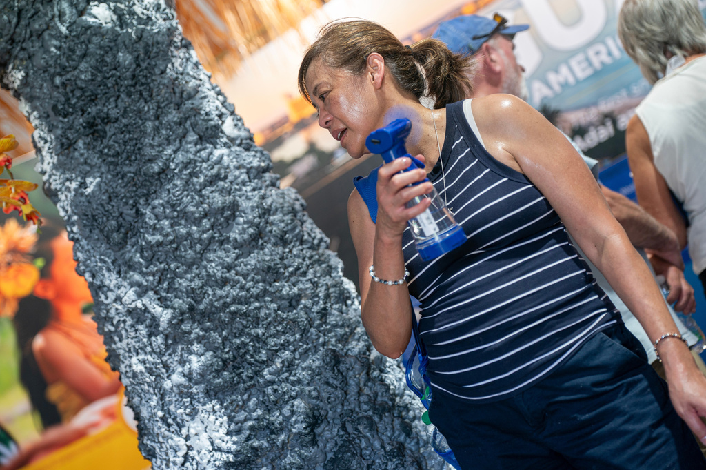 FILE - A visitor to the Guam tent uses a fan to cool down while attending the Great American State Fair on the National Mall, July 1, 2026, in Washington. (AP Photo/Nathan Howard, File)