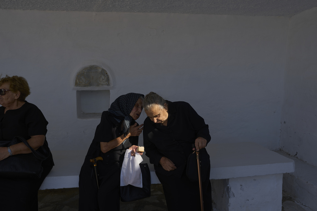 Ioanna Louvari, 96, talks with another elderly woman during a liturgy at the family-owned Agios Sostis chapel on the island of Tinos, Greece, Monday, Sept. 8, 2025. (AP Photo/Petros Giannakouris)