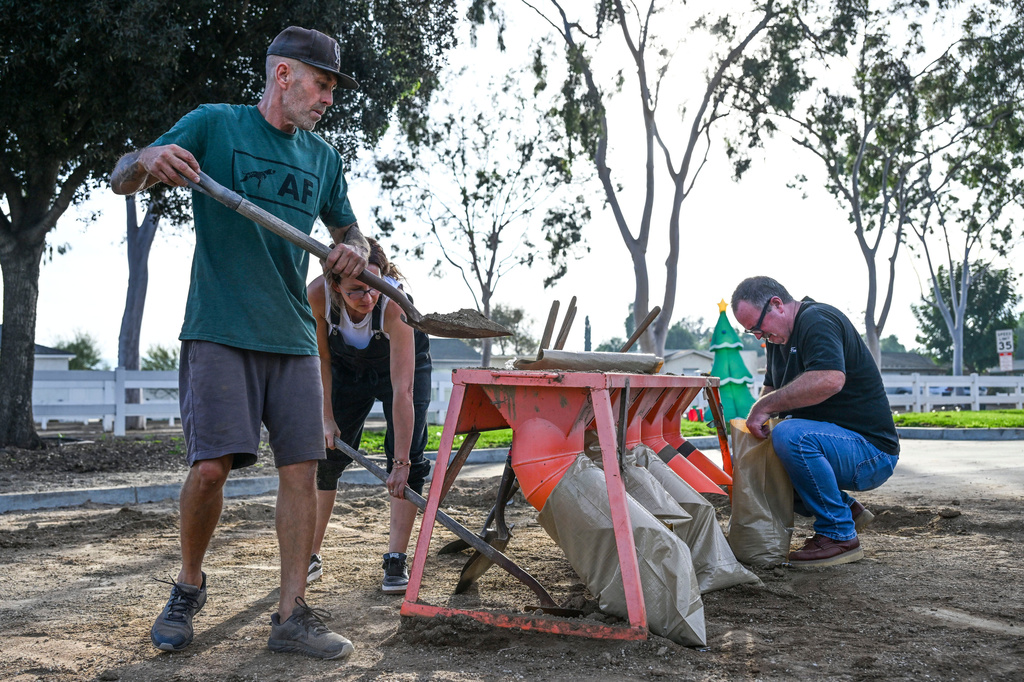 Norco resident Robert Gray and Terry McCauley fill sandbags at Riverside County fire station in Norco, Calif. on Monday, Dec. 22, 2025, as they prepare for the incoming storm. (Anjali Sharif-Paul/The Orange County Register via AP)