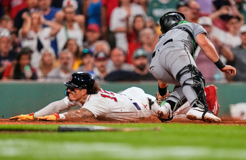 Boston Red Sox's Jarren Duran, left, beats the tag by Chicago White Sox's Drew Romo to score on a sacrifice by Andruw Monasterio during the seventh inning of a baseball game, Wednesday, Aug. 5, 2026, in Boston. (AP Photo/Charles Krupa)
