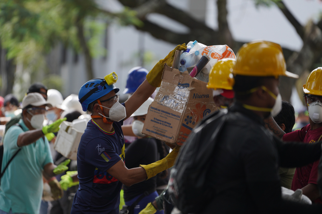 Rescuers pass food packages for rescue teams and volunteers searching through the rubble four days after an earthquake hit Cali, Colombia, Friday, Aug. 14, 2026. (AP Photo/Ivan Valencia)