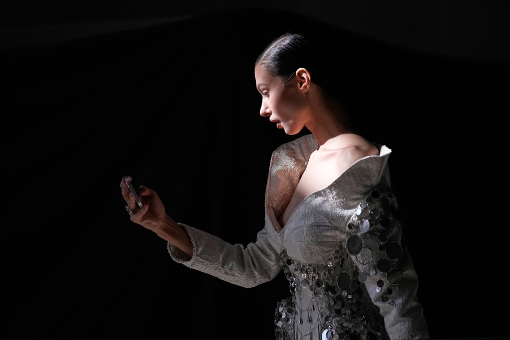 A model wearing a creation by students of the Institute of Business and Design B&D takes a selfie at the backstage, at the Moscow Fashion Week in Moscow, on Thursday, March 19, 2026. (AP Photo/Alexander Zemlianichenko)