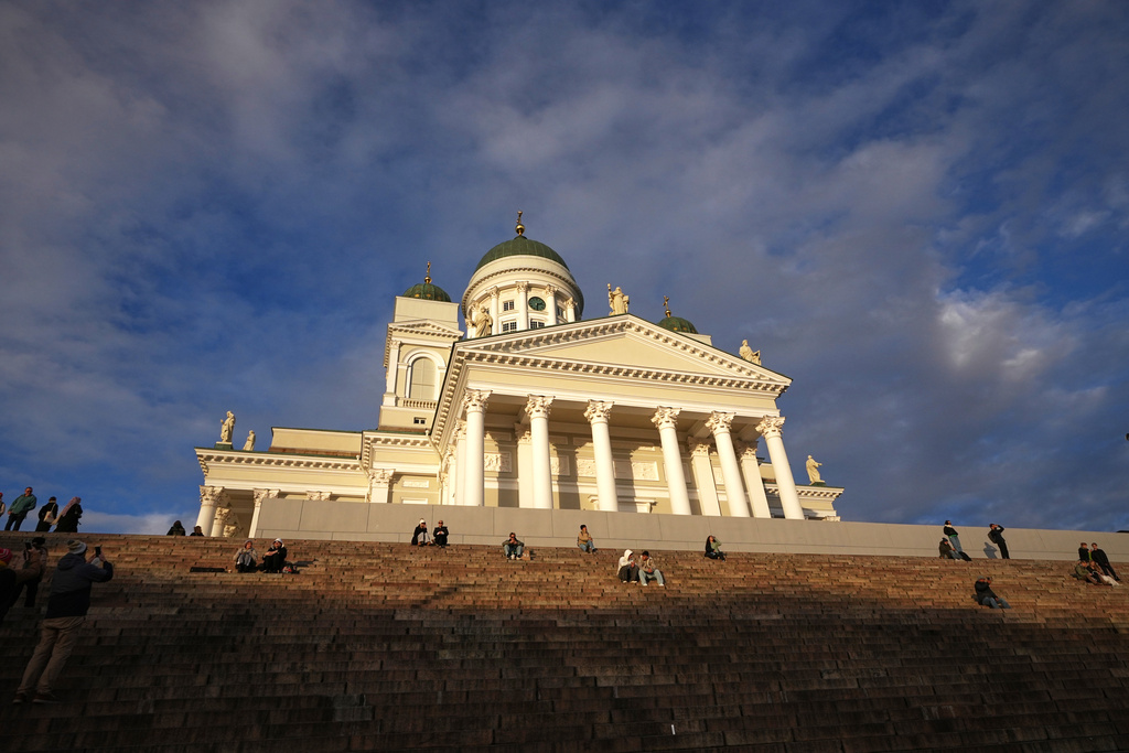 People enjoy the sunny weather with the Helsinki Cathedral of the background in Helsinki, Finland, Friday, Nov. 14, 2025. (AP Photo/Sergei Grits)