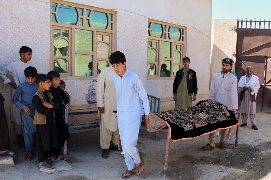 The body of a person killed in a strike that hit a house is carried on a bed frame in the Momand Dara district of Nangarhar province, Afghanistan, near the border with Pakistan, Friday, March 13, 2026. (AP Photo/Hedayat Shah)