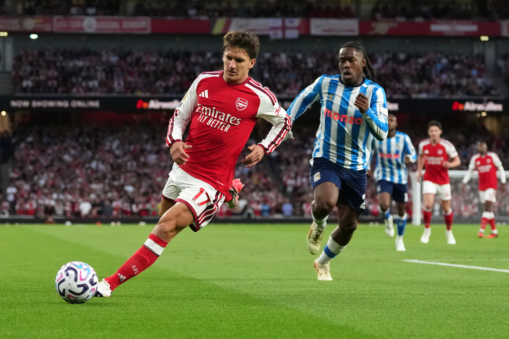 Arsenal's Christos Tzolis runs with the ball followed by Coventry City's Brandon Thomas-Asante during the English Premier League soccer match between Arsenal and Coventry City in London, Friday, Aug. 21, 2026. (AP Photo/Kirsty Wigglesworth)
