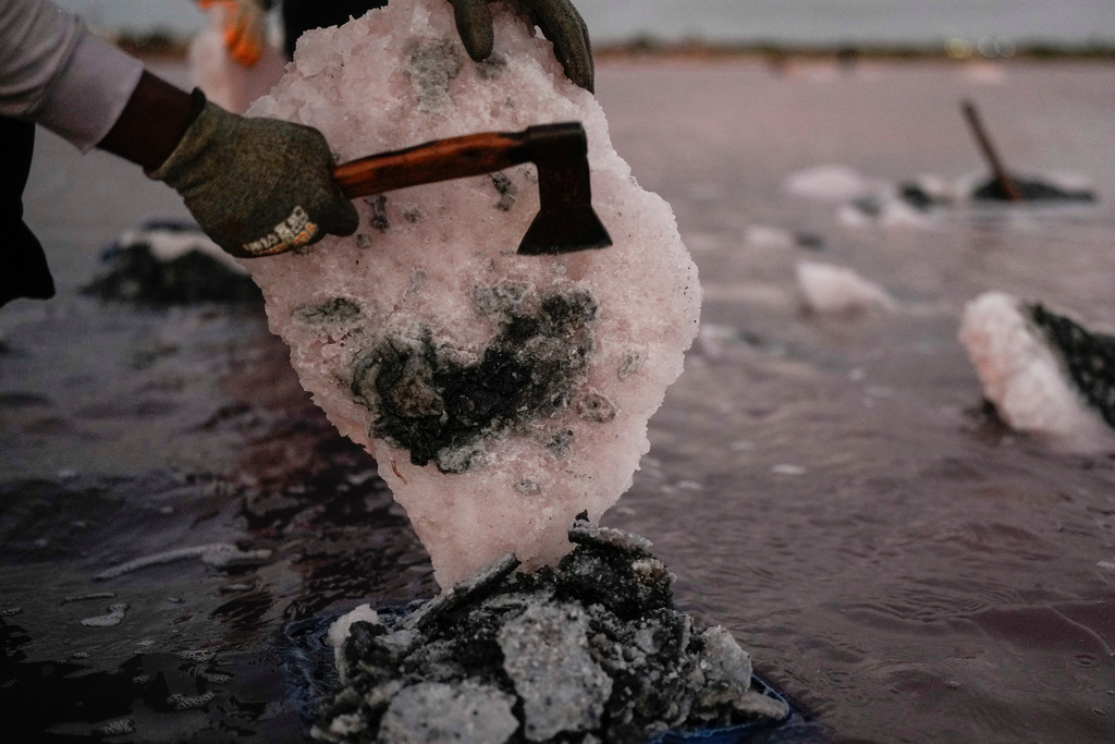 Jose Gabriel Sanchez cuts a block of salt at the Salinas de Las Cumaraguas salt ponds on the Paraguana Peninsula in Falcon state, Venezuela, Thursday, Jan. 15, 2026. (AP Photo/Matias Delacroix)