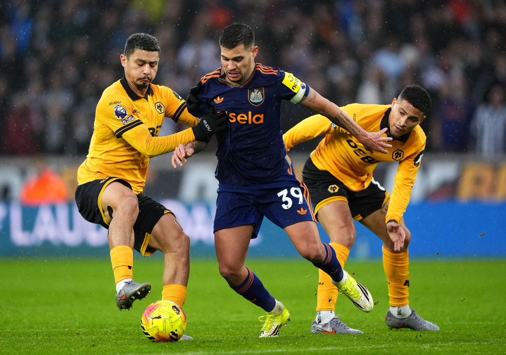 Wolverhampton Wanderers' Andre, left, and Joao Gomes challenge Newcastle United's Bruno Guimaraes during the English Premier League soccer match between Wolves and Newcastle United in Wolverhampton, England, Sunday Jan. 18, 2026. (Mike Egerton/PA via AP)