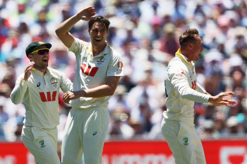 Australia's Pat Cummins, centre, celebrates with teammate Australia's Marnus Labuschagne, right, after dismissing England's Ollie Pope during play on day four of the third Ashes cricket test between England and Australia in Adelaide, Australia, Saturday, Dec. 20, 2025. (AP Photo/James Elsby)