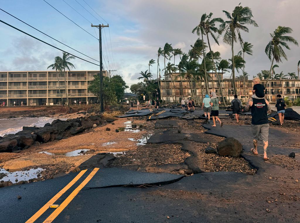 This photo taken with a smartphone, People walk past damage caused by Hurricane Lowell on Tuesday, Sept. 8, 2026 in Poʻipū on Kauaʻi's south shore, in Hawaii. (Guy Miller/Honolulu Civil Beat via AP)