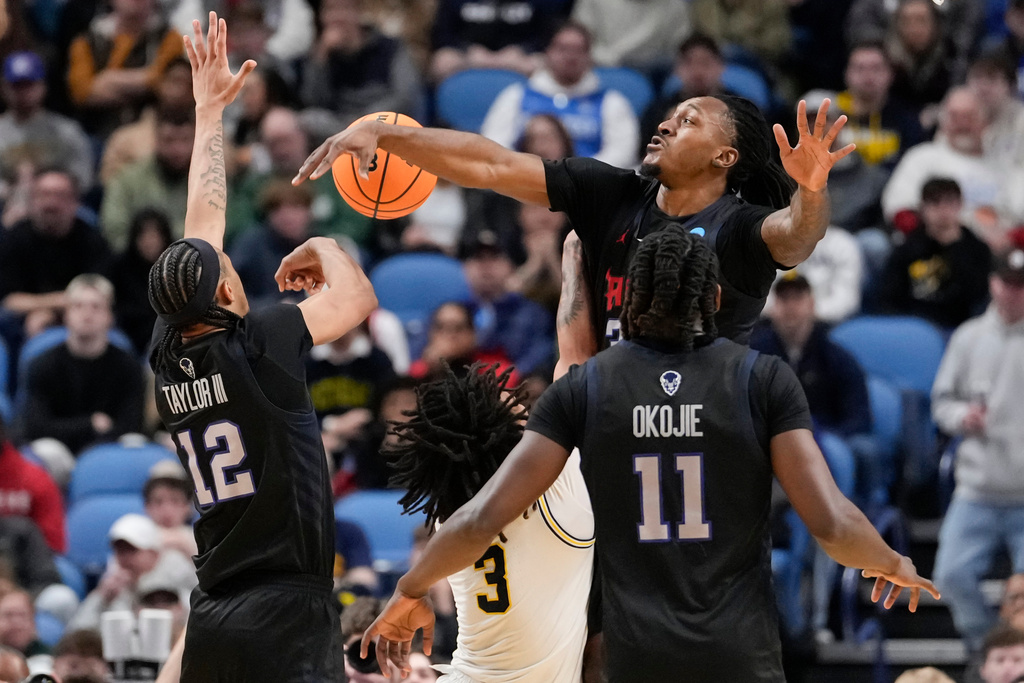 Howard guard Bryce Harris, top right, blocks Michigan guard Elliot Cadeau (3) during the first half in the first round of the NCAA college basketball tournament, Thursday, March 19, 2026, in Buffalo, N.Y. (AP Photo/Yuki Iwamura)
