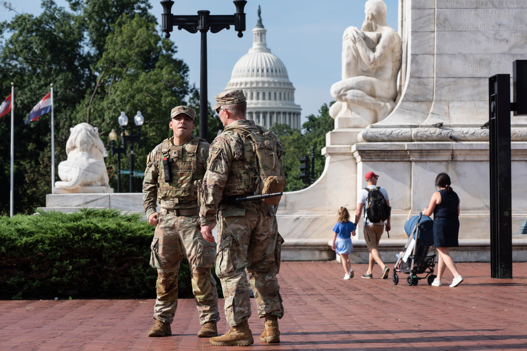 National Guard personnel keep watch as travelers arrive at the entrance to Union Station near the Capitol, in Washington, Thursday, Aug. 14, 2025. (AP Photo/J. Scott Applewhite)