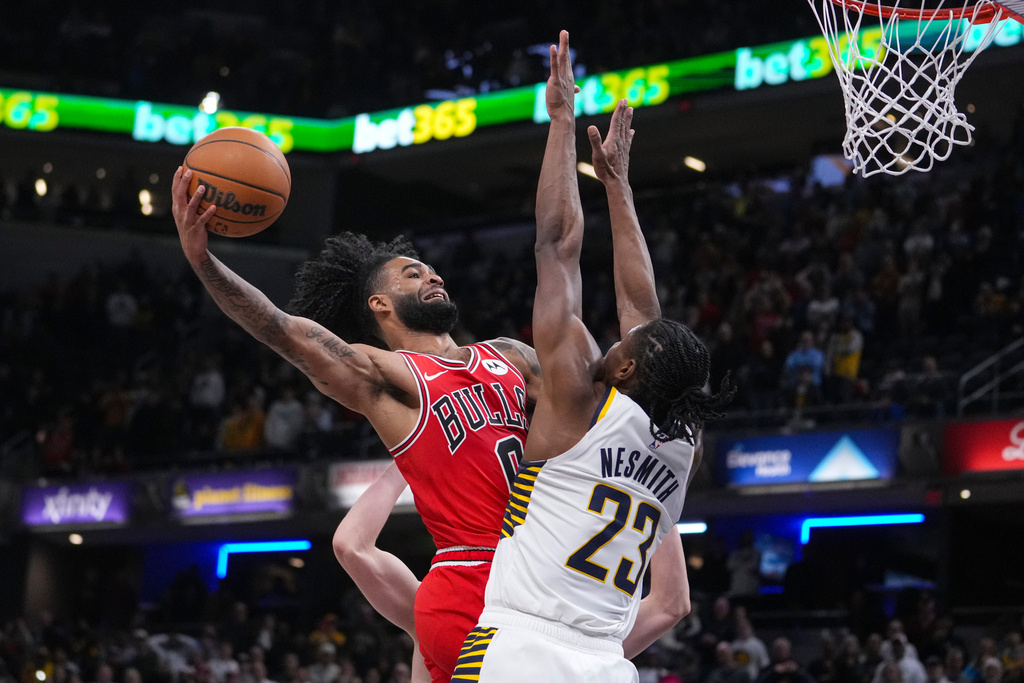 Chicago Bulls guard Coby White (0) misses a shot over Indiana Pacers guard Aaron Nesmith (23) during the second half of an NBA basketball game in Indianapolis, Wednesday, Jan. 28, 2026. (AP Photo/Michael Conroy)