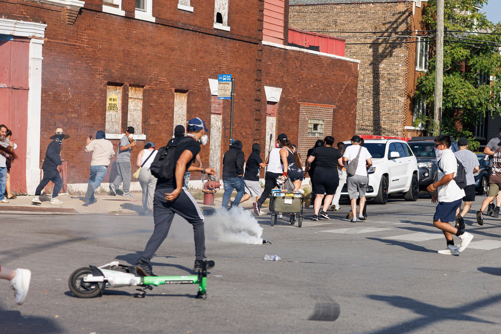 A gas canister erupts on the street in the Brighton Park neighborhood of Chicago, on Saturday, Oct. 4, 2025, after protesters learned that U.S. Border Patrol shot a woman Saturday morning on Chicago's Southwest Side. (Anthony Vazquez/Chicago Sun-Times via AP)