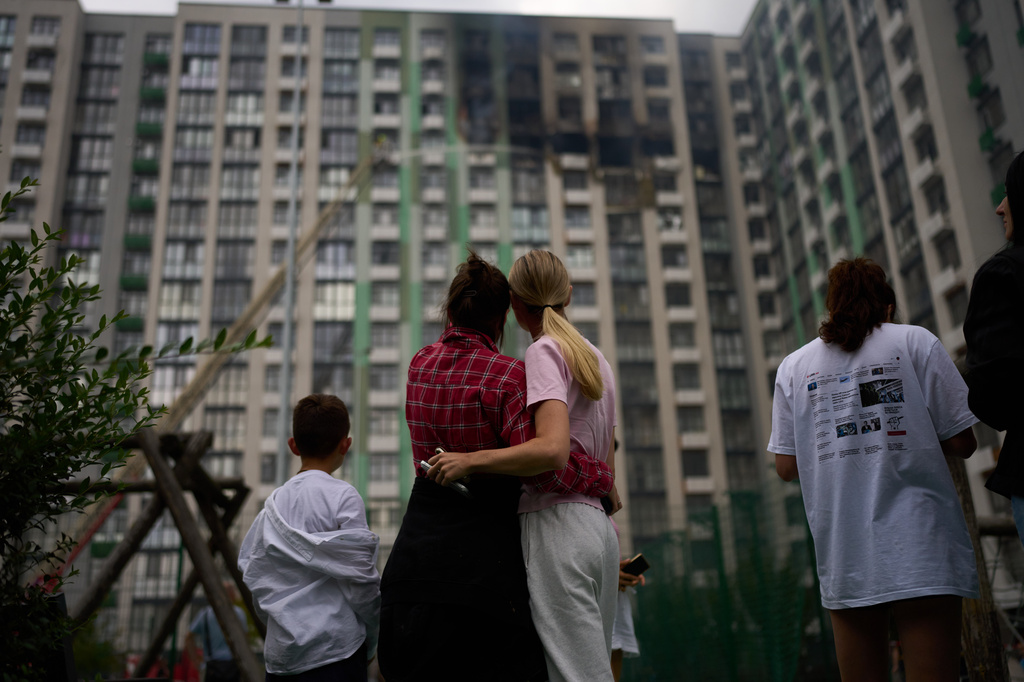 Locals watch as firefighters work after a Russian drone attack struck a residential building in Kyiv, Tuesday, Sept. 1, 2026. (AP Photo/Francisco Seco)