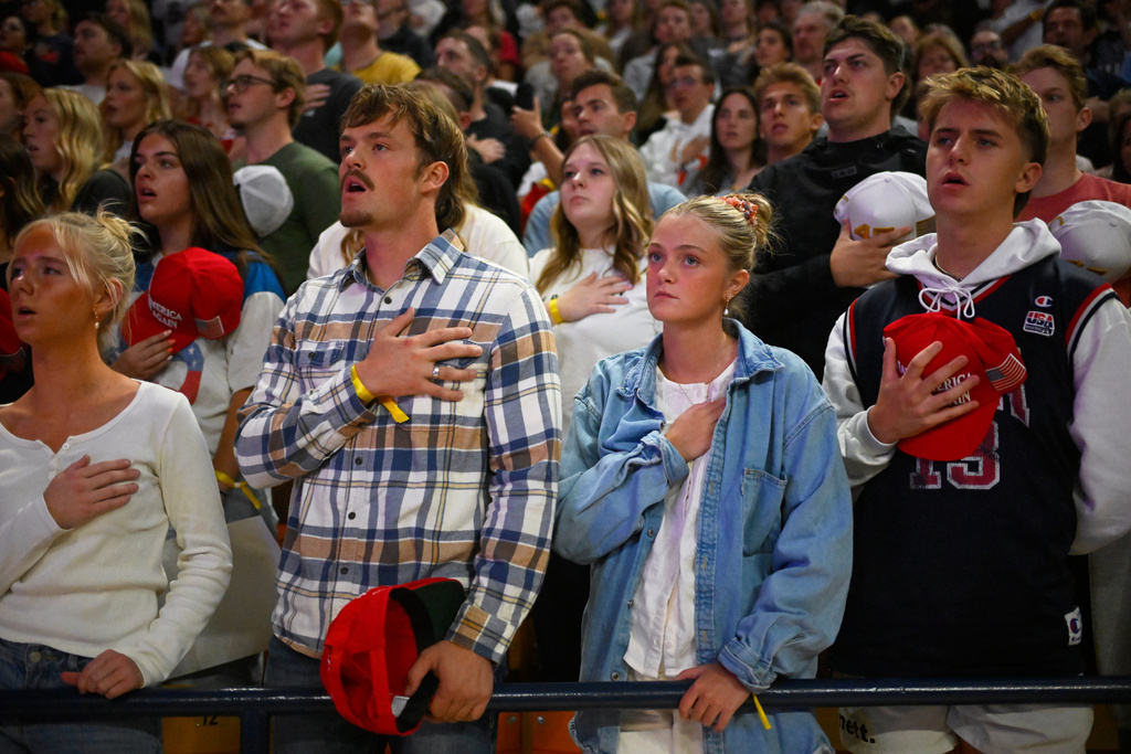 People stand for the national anthem during a Turning Point USA rally at Utah State University, as a part of the organization's push to memorialize Charlie Kirk, Tuesday, Sept. 30, 2025, in Logan, Utah. (AP Photo/Alex Goodlett)