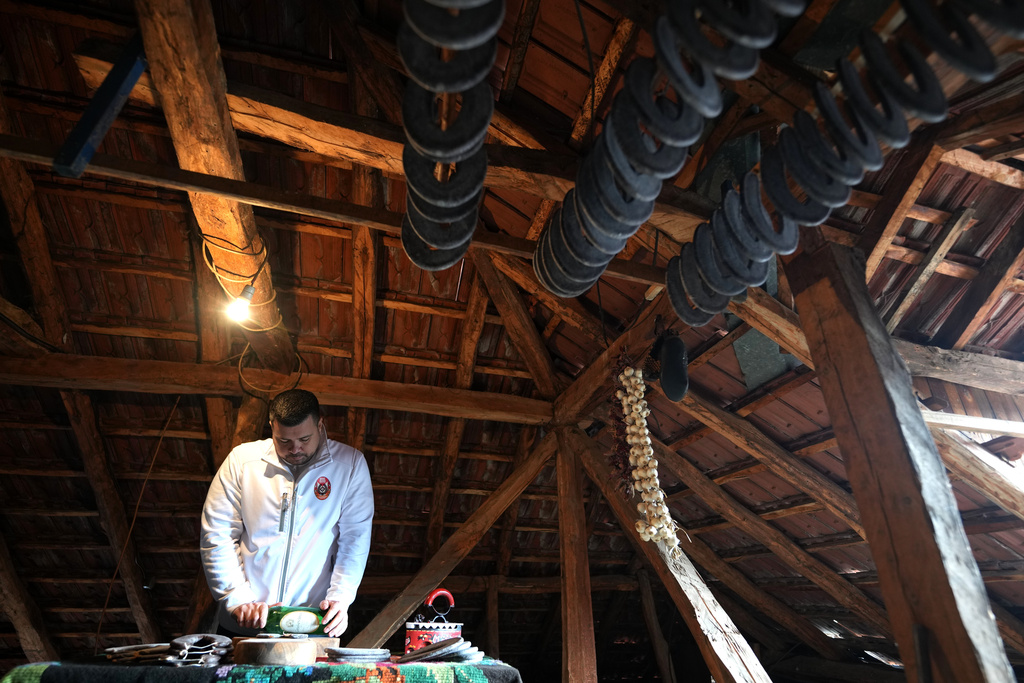 Misa Rajic irons sausage using a glass bottle in the attic of his home in Pirot, Serbia, on Feb. 13, 2026. (AP Photo/Darko Vojinovic)