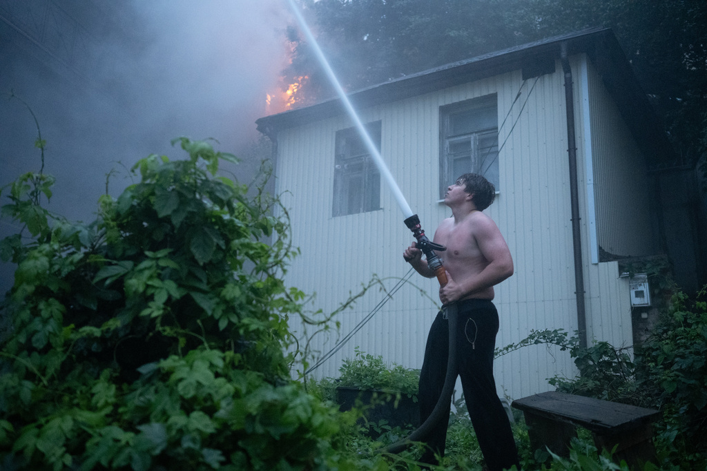 A local resident uses a firehose to extinguish a fire at a building following an overnight Russian attack in Kyiv, Ukraine, Monday, June 15, 2026. (AP Photo/Danylo Antoniuk)