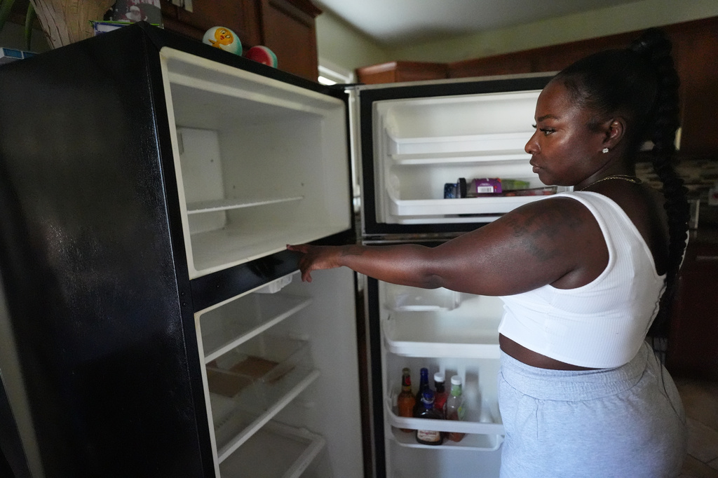 Shatiya Hardin checks her refrigerator after power outages at her home in Gary, Ind., Thursday, Aug. 20, 2026, more than a week after a deadly storm passes through the area. (AP Photo/Nam Y. Huh)