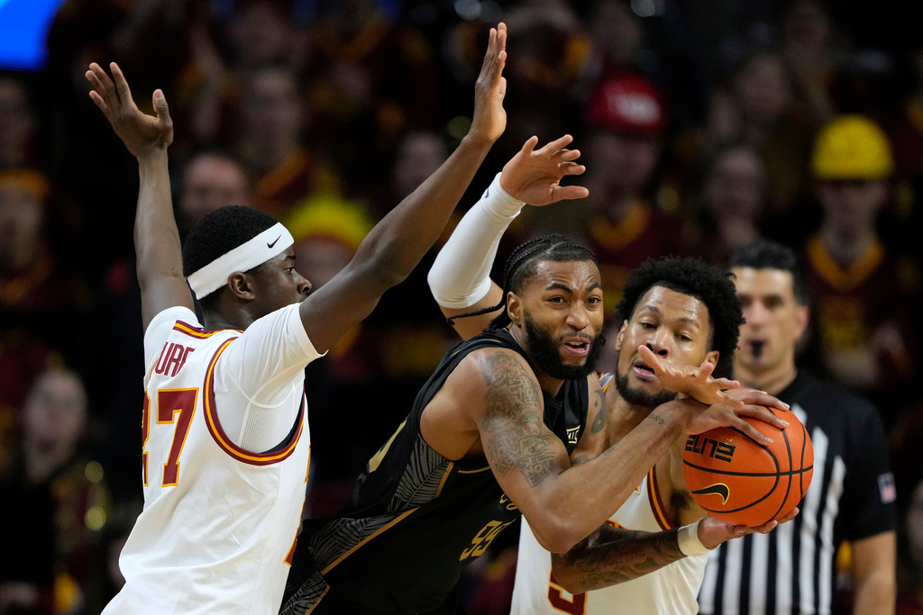 Central Florida forward Jordan Burks, center, passes between Iowa State guard Killyan Toure, left, and Iowa State forward Joshua Jefferson, right, during the second half of an NCAA college basketball game, Tuesday, Jan. 20, 2026, in Ames, Iowa. (AP Photo/Charlie Neibergall)