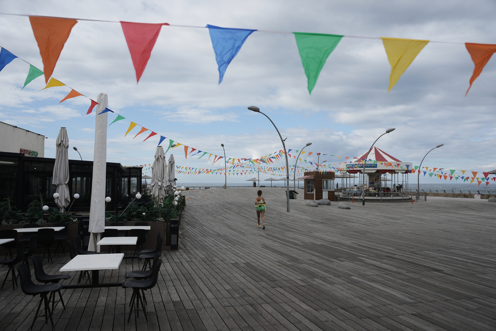 A woman runs on empty boardwalk at the Tel Aviv , Israel, port after alarms announced that Israel had launched an attack on Iran, Saturday, Feb. 28, 2026. (AP Photo/Oded Balilty)