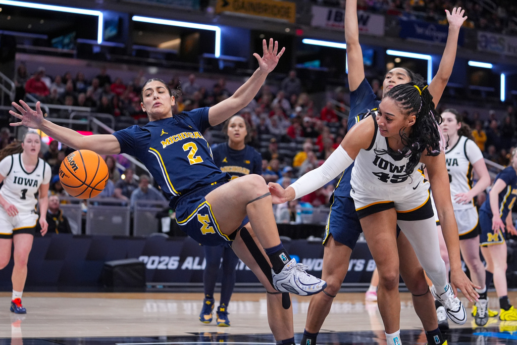 Michigan guard Macy Brown (2) falls after fouling Iowa forward Hannah Stuelke (45) in the second half of an NCAA college basketball game in the semifinals of the Big Ten Conference tournament, Saturday, March 7, 2026 in Indianapolis. (AP Photo/Michael Conroy)