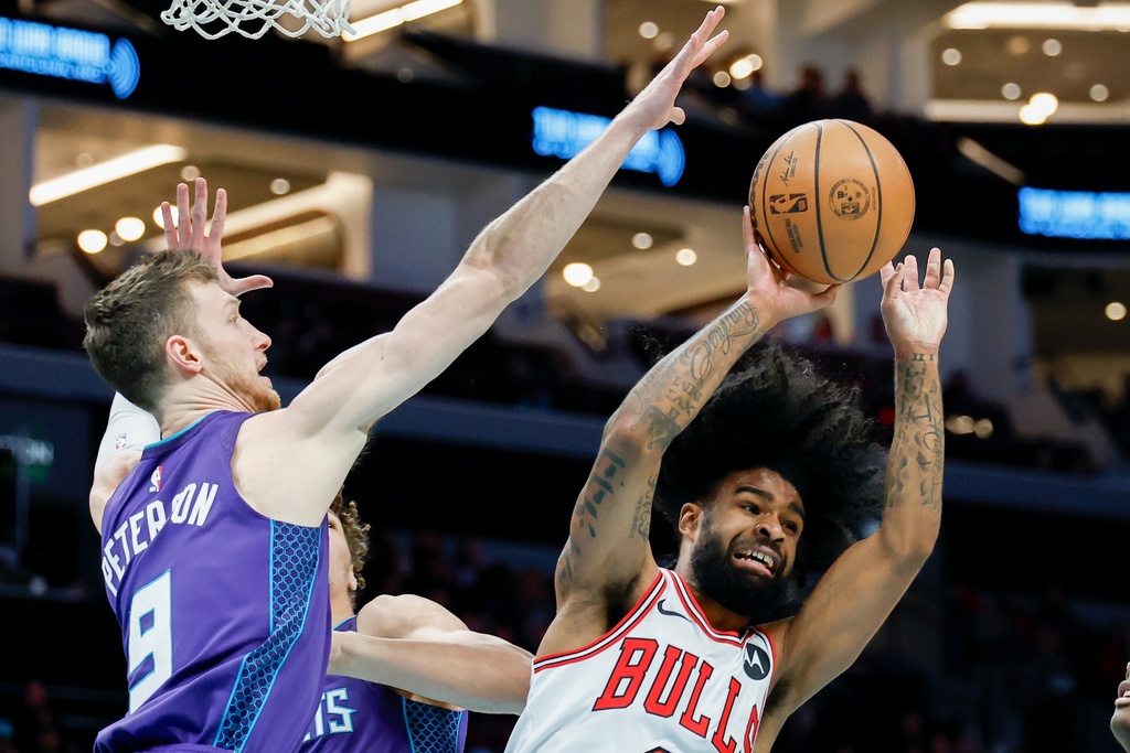 Chicago Bulls guard Coby White, right, looks to pass the ball against Charlotte Hornets forward Drew Peterson, left, during the first half of an NBA basketball game in Charlotte, N.C., Friday, Dec. 12, 2025. (AP Photo/Nell Redmond)