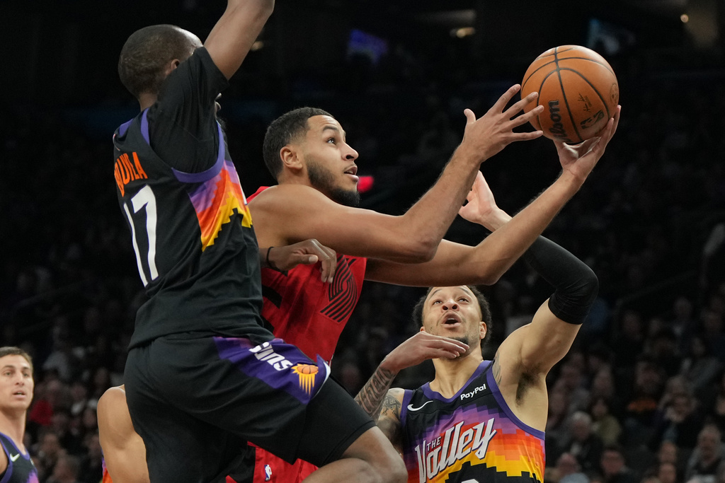 Portland Trail Blazers forward Kris Murray, center, drives between Phoenix Suns guard Jamaree Bouyea (17) and guard Amir Coffey, right, during the first half of an NBA basketball game, Sunday, Feb. 22, 2026, in Phoenix. (AP Photo/Rick Scuteri)