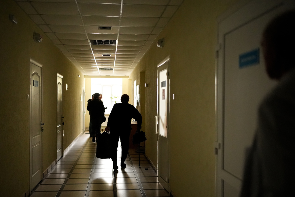 A patient walks through a darkened hallway of Shostka Central District Hospital during a rolling blackout, Thursday, Oct. 16, 2025, in Shostka, Ukraine. (AP Photo/Julia Demaree Nikhinson)