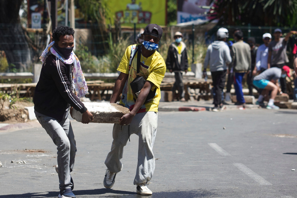 Protesters carry a concrete slab to help barricade the street during a protest calling for the president to step down in Antananarivo, Madagascar, Thursday, Oct. 9, 2025. (AP Photo/Alexander Joe)